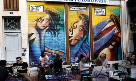 People sit on the tables of a cafe in central Athens.