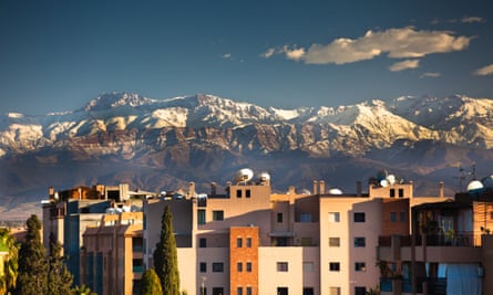View of Marrakech buildings, with snow-capped Atlas Mountains as backdrop.