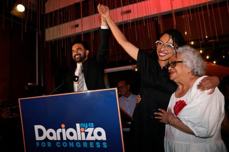 Two women hug while one of them holds man’s hand in the air