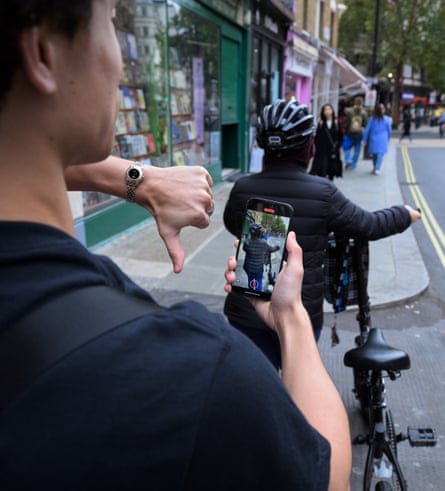 Roh films a woman from behind who is walking while pushing her bike on the pavement.