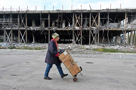 A local resident carries her cart by a destroyed building in Izium.