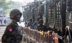 A file shot of soldiers standing next to military vehicles as people gather in Yangon, Myanmar, in February 2021 to protest against the military coup