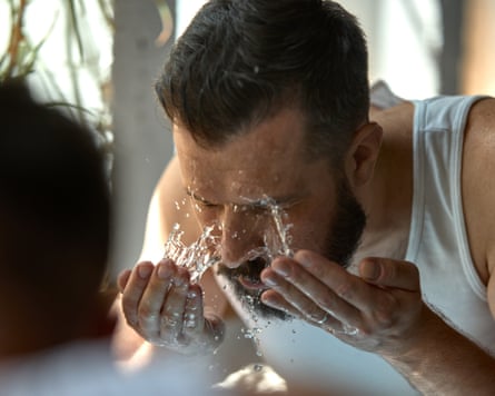 Man splashes h2o connected his face, droplets glisten connected his skin