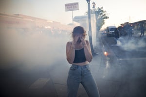 A protestor reacts as she walks through a cloud of teargas