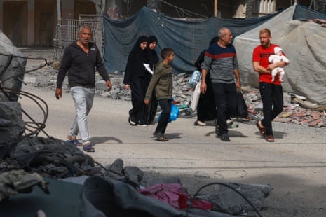 A Palestinian family walks past debris in Rafah, in the southern Gaza Strip.