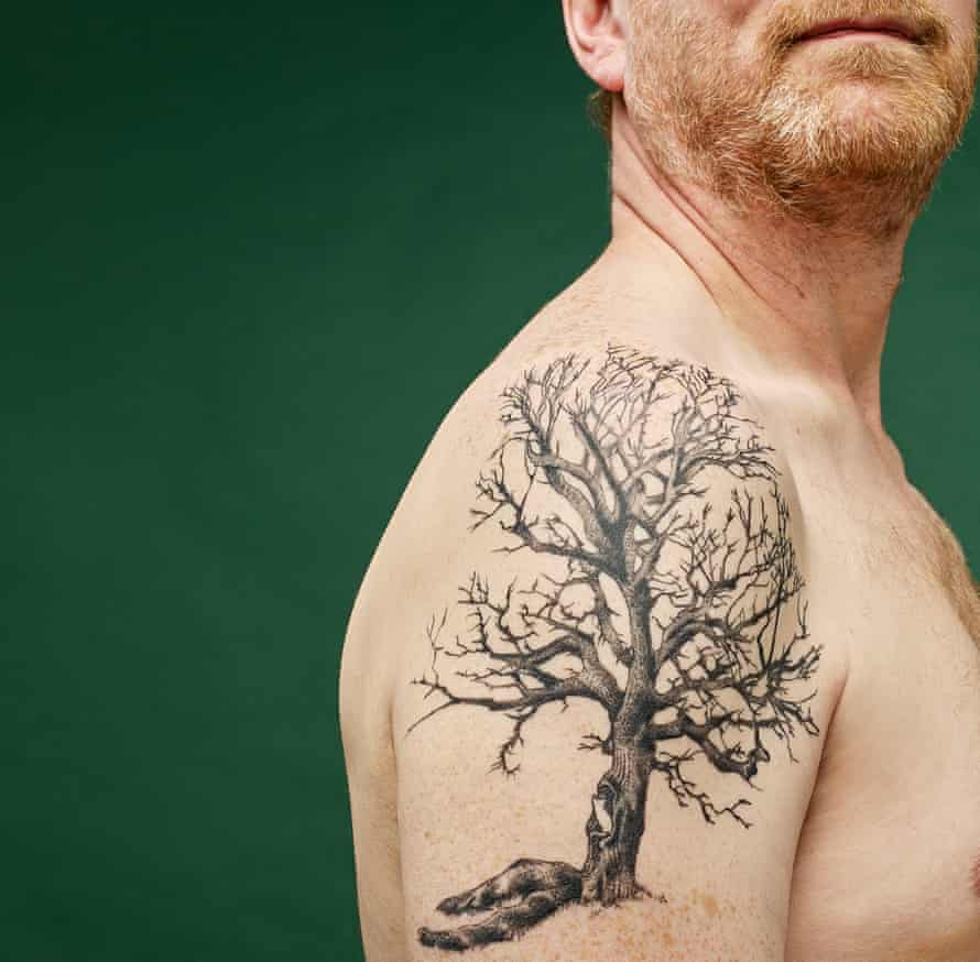 Right arm and chin of writer Michael Hann, with tree tattoo going over his shoulder, against green background