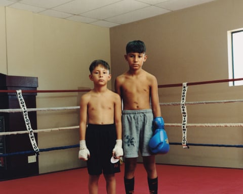 Two young boys in a boxing ring, stand still looking to camera