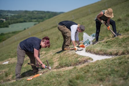 Three volunteers pack chalk on a steep hill