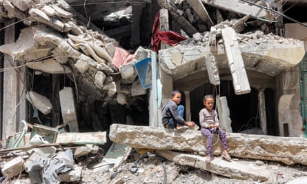A boy and girl sitting in the ruins of a destroyed building in Gaza City.