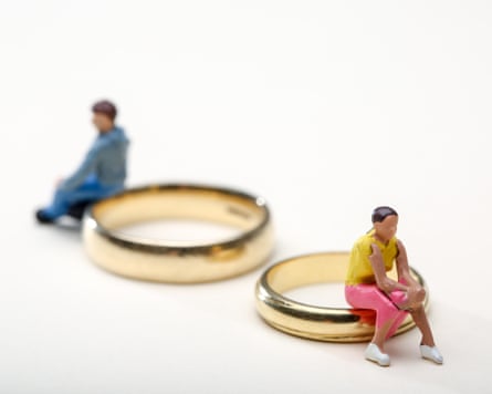 Concept image of a couple sat on wedding rings to illustrate divorce and separation