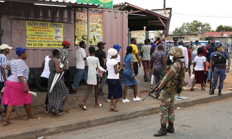 A member of the South African national defence force keeps watch as shoppers leave the Shoprite grocery store