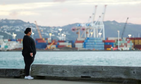 A pedestrian wearing a face mask looks out over Wellington Harbour, New Zealand.