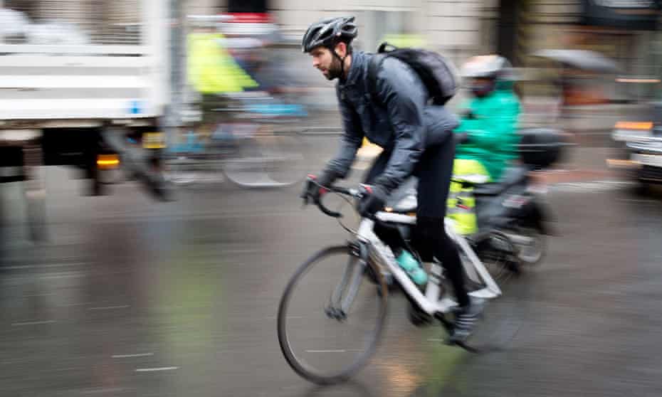 A helmeted cyclist on the streets of London.