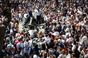 People surround a military vehicle as it parades during the military ceremony