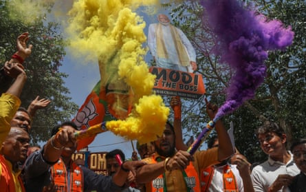 A group of men celebrate with yellow and purple smoke.