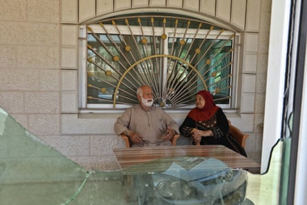 Fahmiyh Shelaby, 79, and her husband, seen through a window in their home broken during the attack on Turmus Ayya.