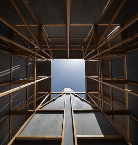 A view of a small blue square of blue sky, looking up, surrounded by wooden walls.