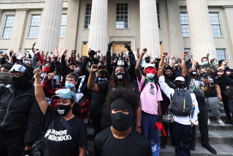 Demonstrators raise their fists as they gather on the steps of the Louisville Metro Hall on Thursday.
