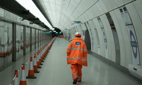 A member of the construction team walks past a sign on the platform of Farringdon Crossrail station
