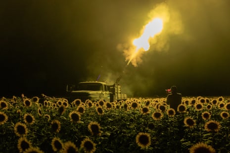 Ukrainian servicemen, standing in a sunflower field at night, retaliate against a Russian drone attack