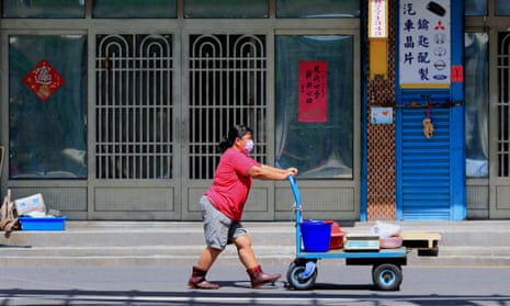 A lady with a mask pushes a trolley on a roadway at Fenggang Village in Fangshan of Pingtung County