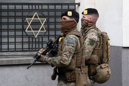 Belgian soldiers patrol outside a synagogue wearing face coverings and carrying guns