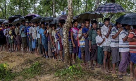 Rohingya  men who crossed  from Myanmar to Bangladesh wait for their turn to collect a bag of rice from aid agencies in Balukhali refugee camp