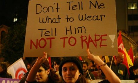 woman holding poster saying 'tell him not to rape'