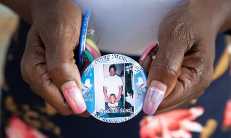 Catherine Walker, mother of Grechario Mack, holds a badge in Los Angeles last year.