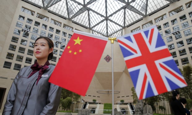 An employee stands next to the Chinese and British flags