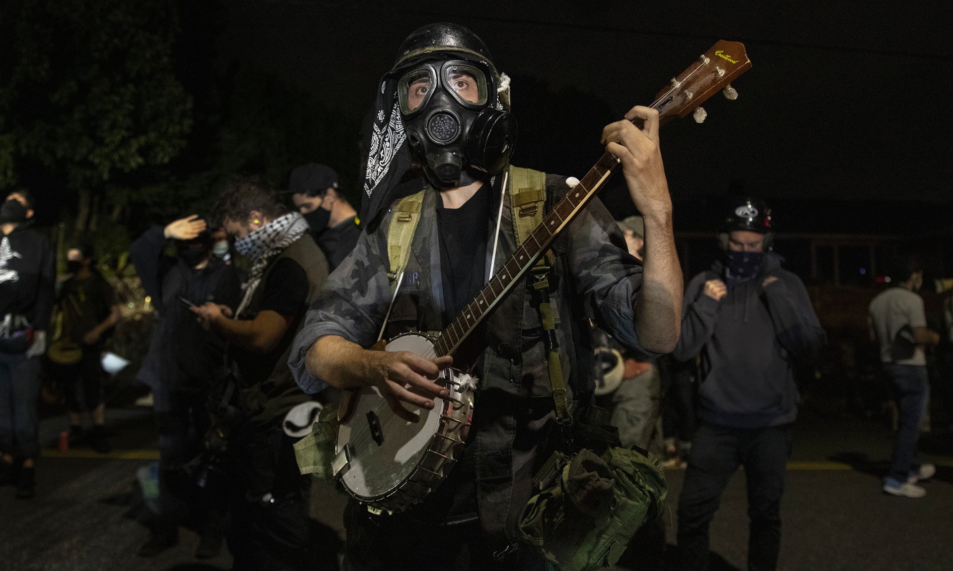 A protester plays a banjo during the nightly protests at a Portland police precinct on Sunday. The protest was declared an ‘unlawful gathering’ by Portland police. Photograph: Paula Bronstein/AP