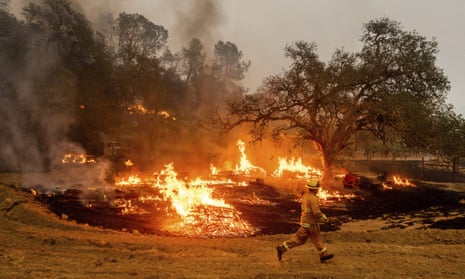 A firefighter runs past flames while battling the Glass Fire in a Calistoga, California, vineyard on 1 October.