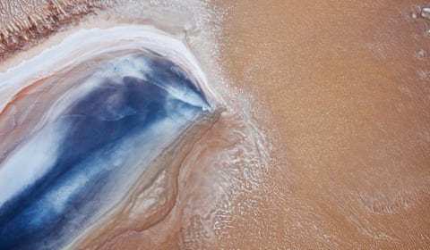 Aerial view of a coastal inlet where blue water meets yellow sand