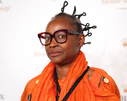 Koyo Kouoh in an orange jacket and glasses