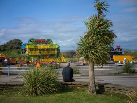 A man sits connected a wall other an quiet playground pinch a fewer fairground-type amusements
