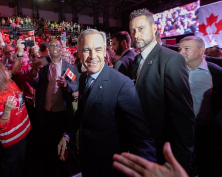 Prime minister Mark Carney smiles while walking through a crowd waving Canadian flags