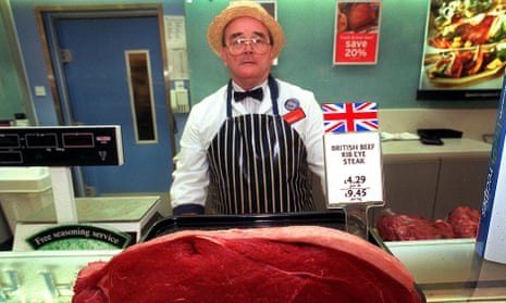 A butcher standing behind a piece of British beef at the meat counter of Sainsbury’s.