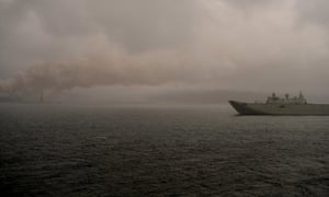 A navy vessel sits in the rain in front of the burning Eden woodchip mill off the coast of New South Wales last month.