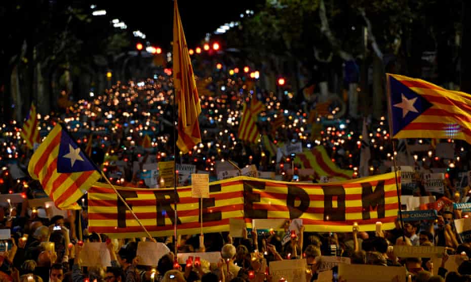 Crowds hold a giant Estelada (pro-independence Catalan flag) reading “Freedom” during candle-lit demonstration in Barcelona against the arrest of two Catalan separatist leaders this week