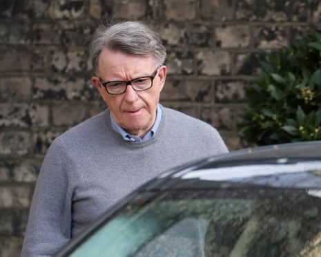 Mandelson in glasses and a grey sweater looks down as he approaches a car door