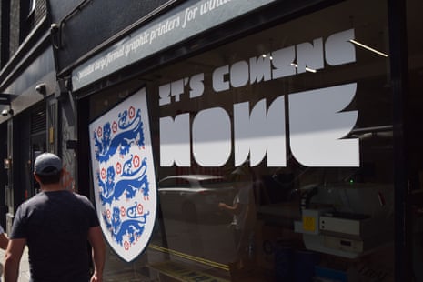 A man walks past an 'It's Coming Home' sign in a shop window in central London