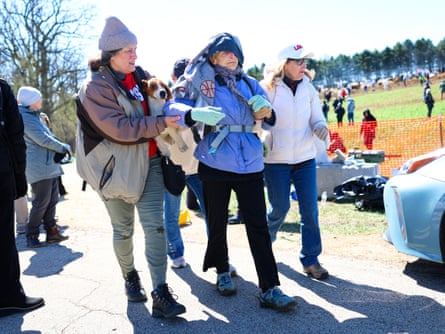 two women help older woman walk outside