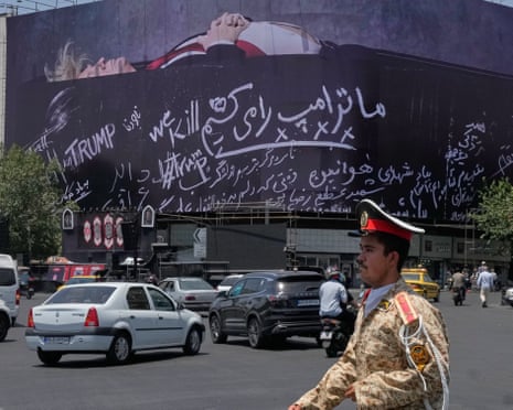 An army cadet walks past a billboard bearing anti-Trump messages at Islamic Revolution Square in downtown Tehran