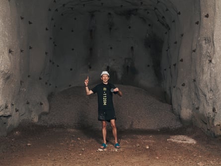 James Mason, who won the world’s deepest marathon, standing in a tunnel holding up a medal