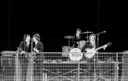 Image of the Beatles on stage with a wire fence in the foreground concealing the bottom half of them