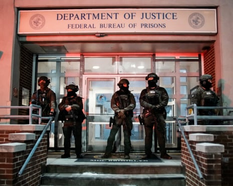 Armed and masked officers outside the closed doors of a DoJ building