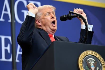 Donald Trump raises his hands in the air as he speaks from a lectern