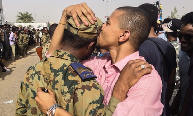 A Sudanese anti-regime protester kisses a soldier on the head.