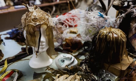 An elaborate headpiece, with two hanging veils covering the eyes, made of a filmy brown material, resting on a dummy’s head