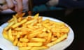A plate of French fried potatoes in a Paris bistro<br>Hands of person eating from a plate of French fried potatoes in a Paris bistro